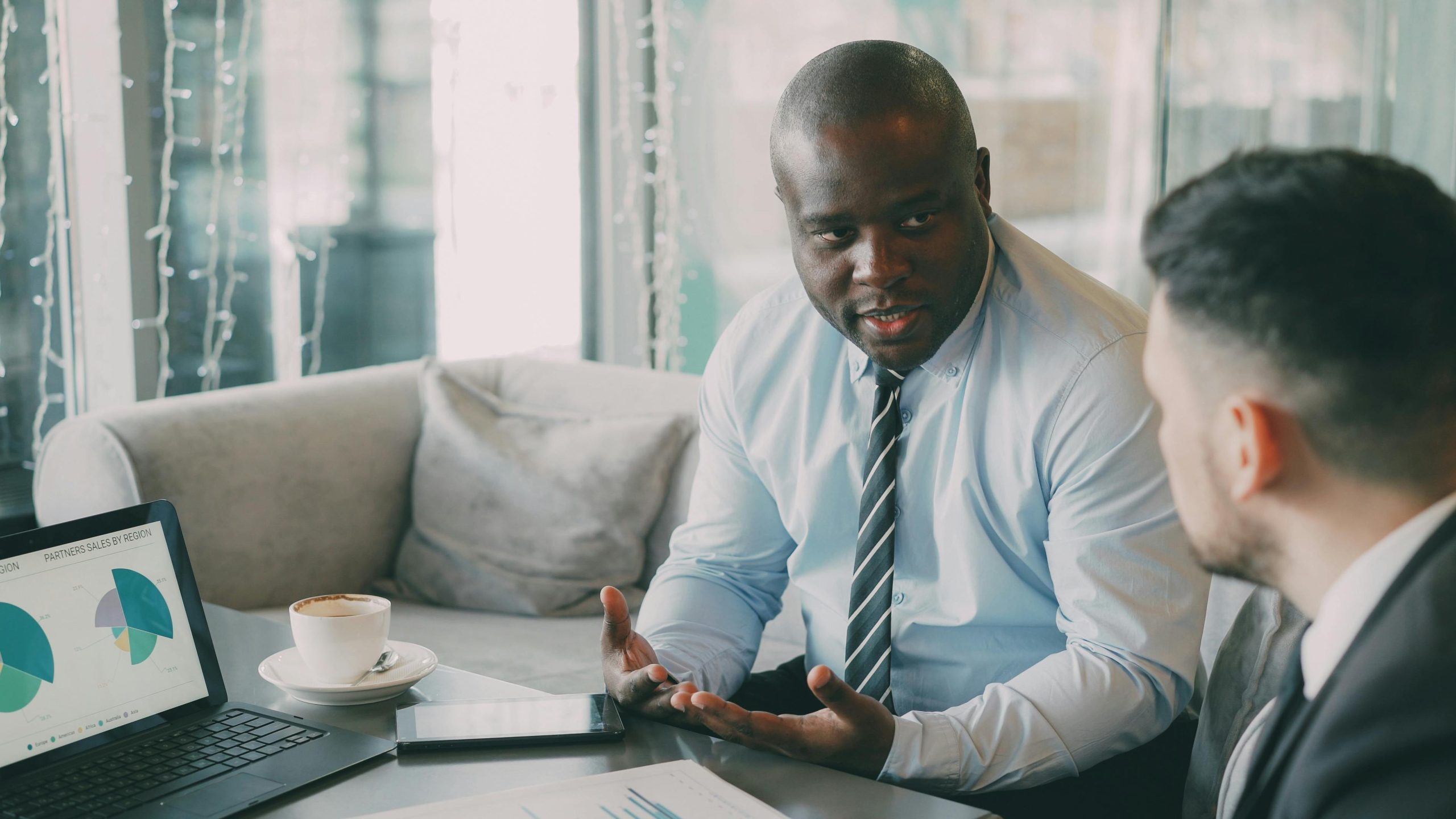 Two businessmen discussing strategies over coffee in a modern cafe.